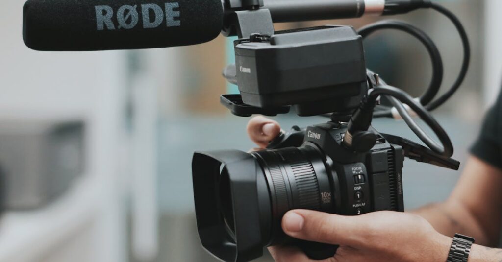 Close-up of hands holding a professional video camera with a RØDE microphone attached.